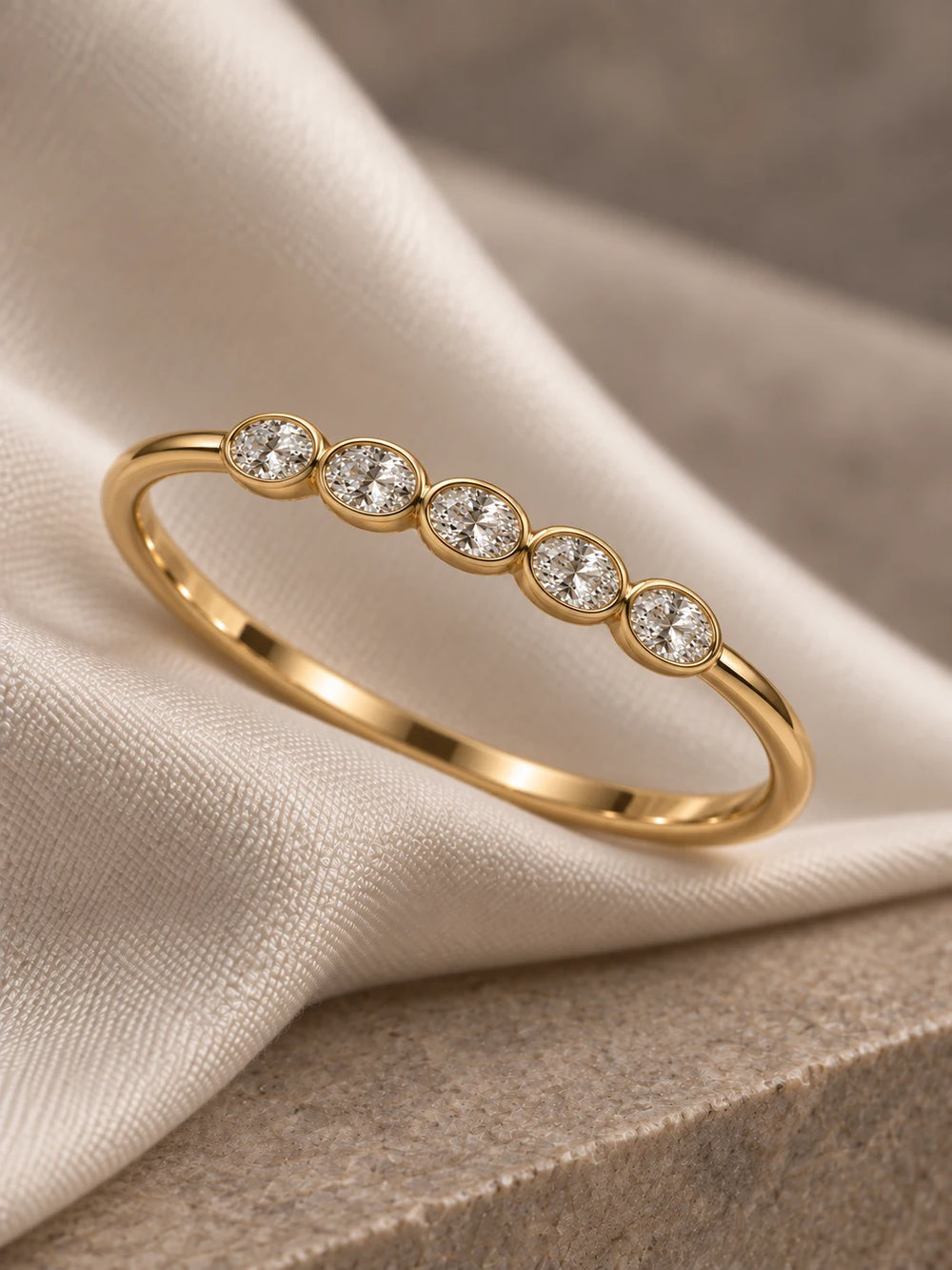 Dainty oval diamond bezel wedding band in yellow gold