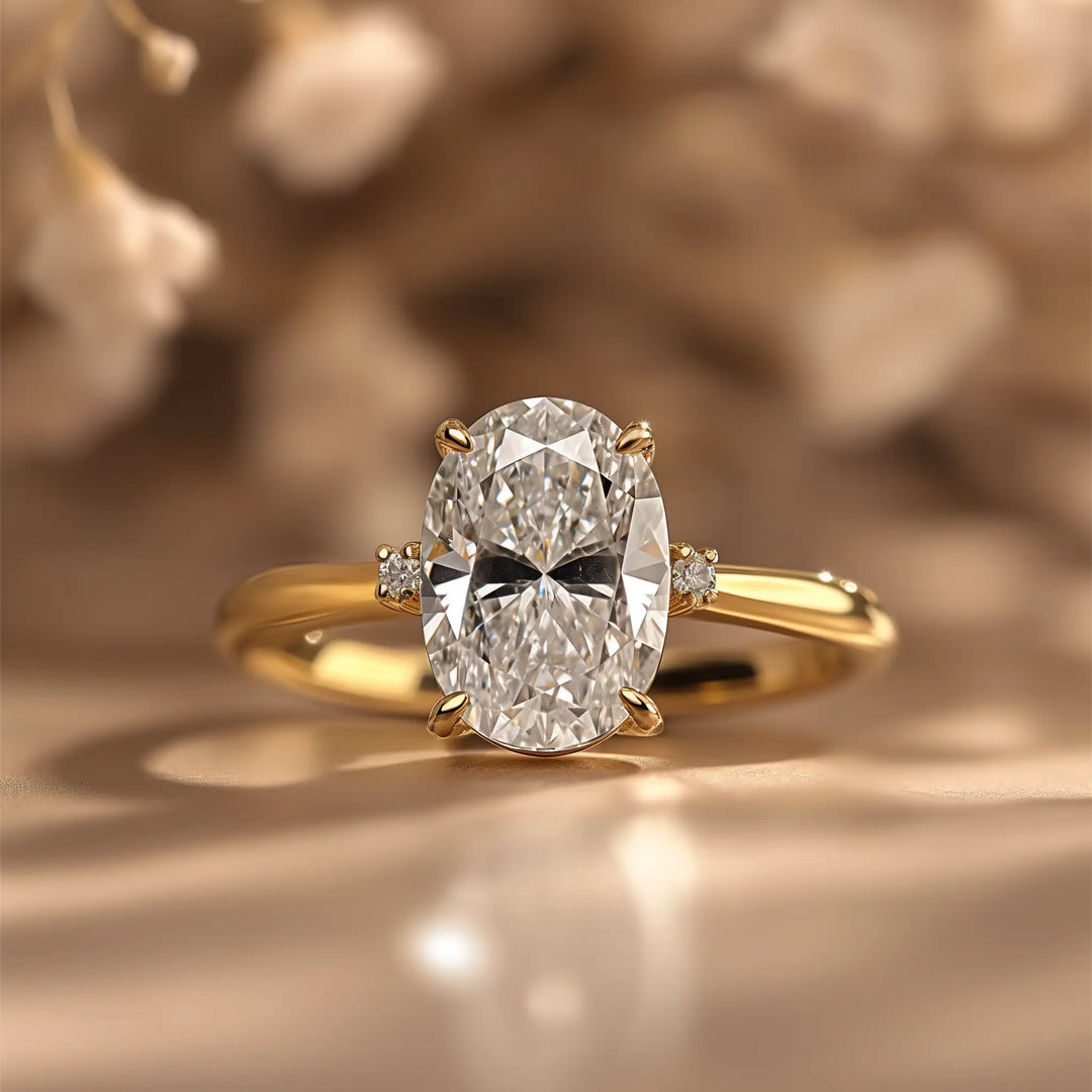 A stunning gold engagement ring showcasing a large, oval-cut diamond flanked by two smaller round diamonds on each side, set against a softly blurred, floral background.