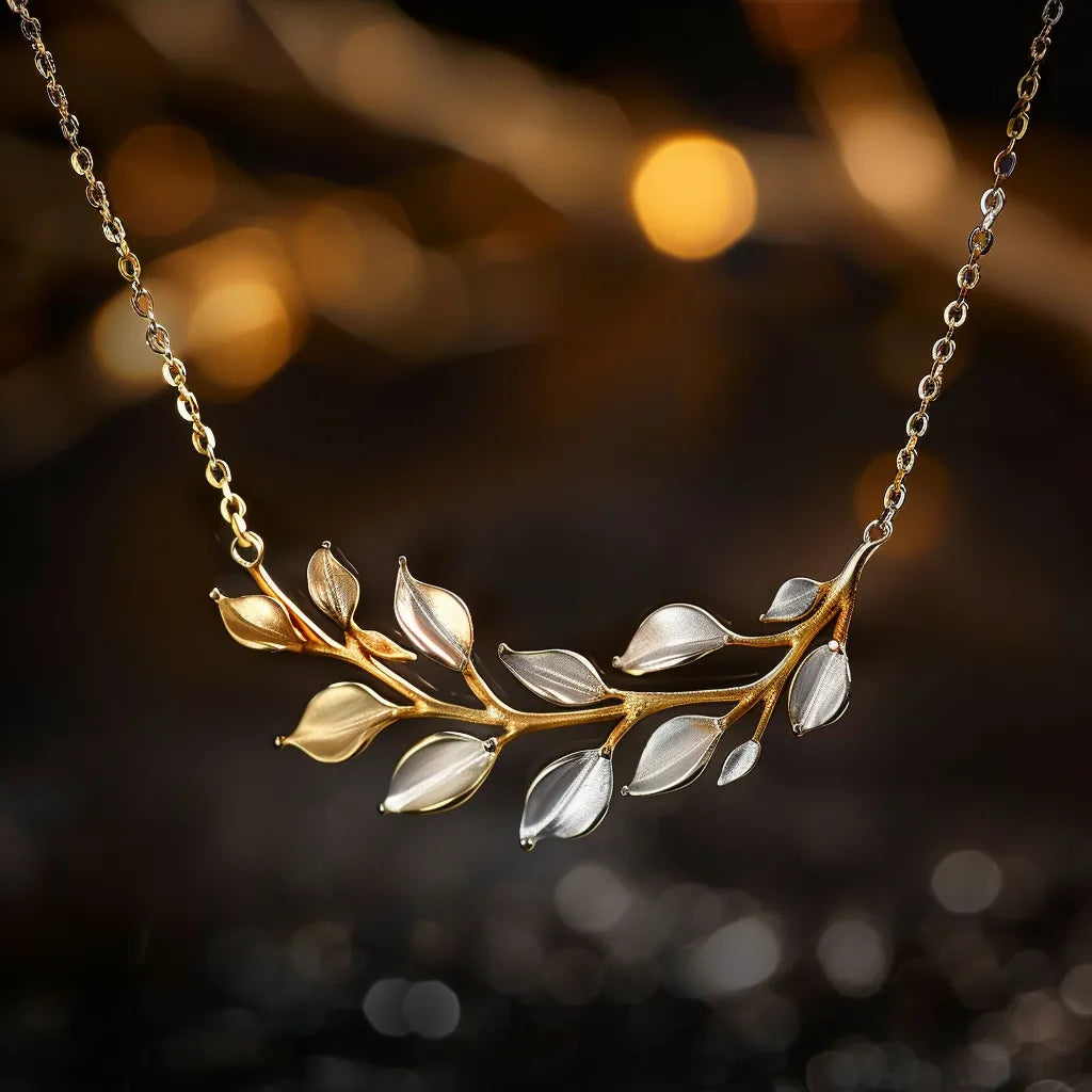 Gold and silver leaf necklace on a delicate chain with a dark, blurred background.