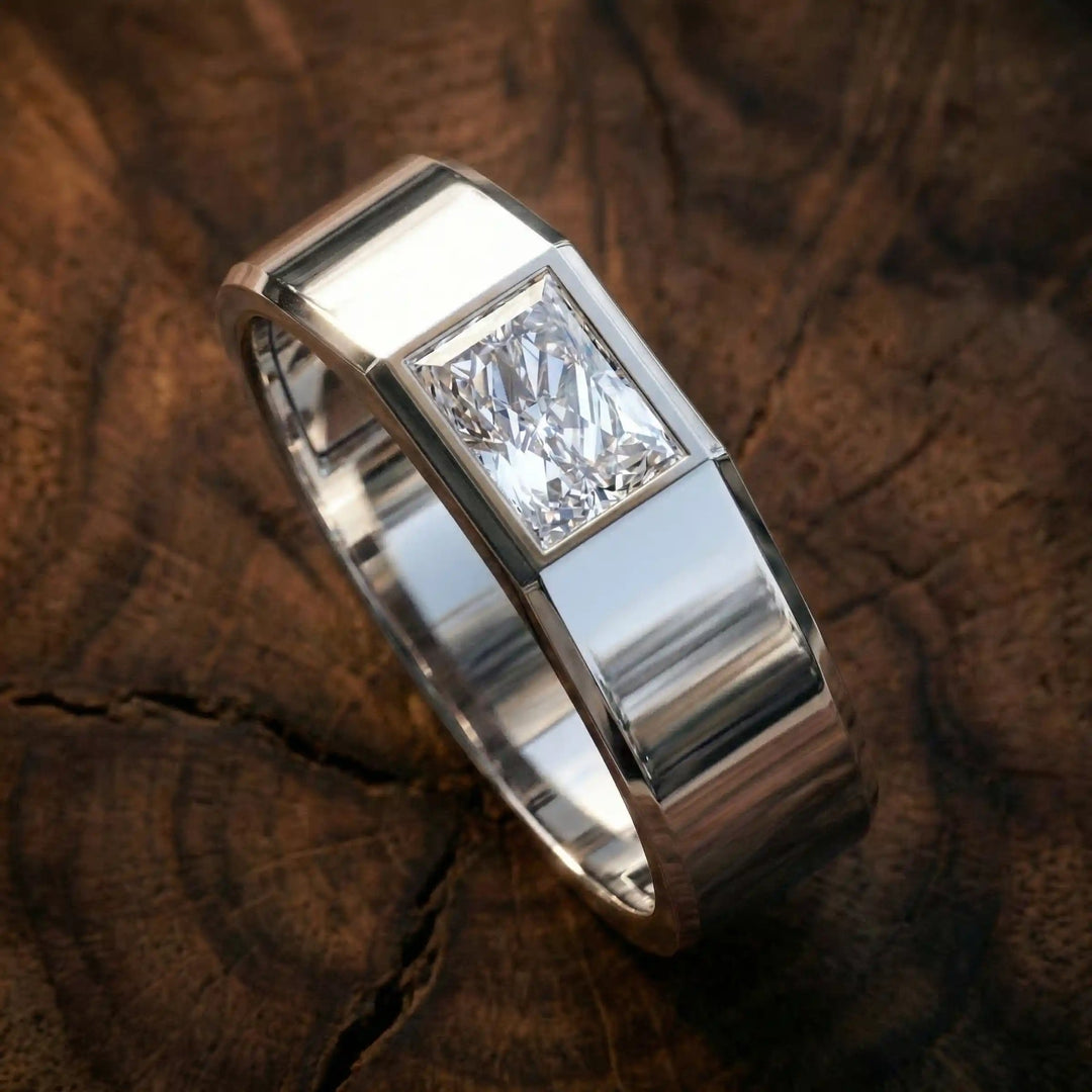 Emerald cut lab-grown diamond bezel ring displayed on wood surface.