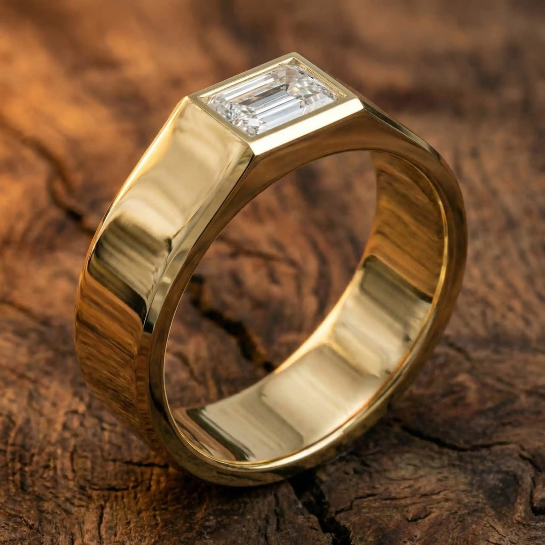 Emerald cut lab-grown diamond bezel ring displayed on wood surface.
