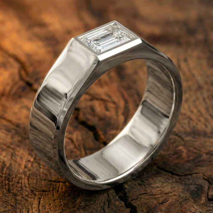 Emerald cut lab-grown diamond bezel ring displayed on wood surface.