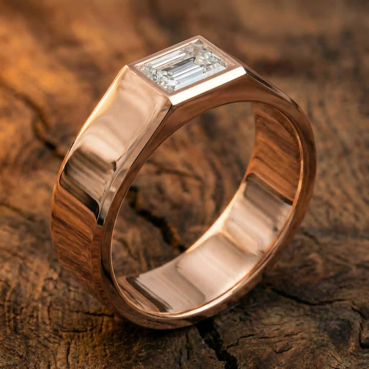 Emerald cut lab-grown diamond bezel ring displayed on wood surface.