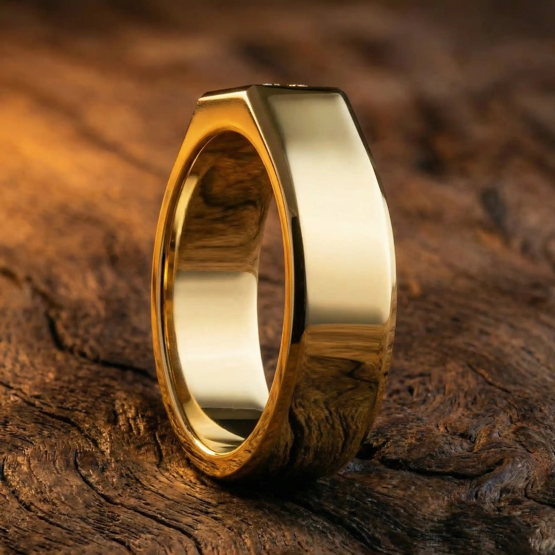 Emerald cut lab-grown diamond bezel ring displayed on wood surface.
