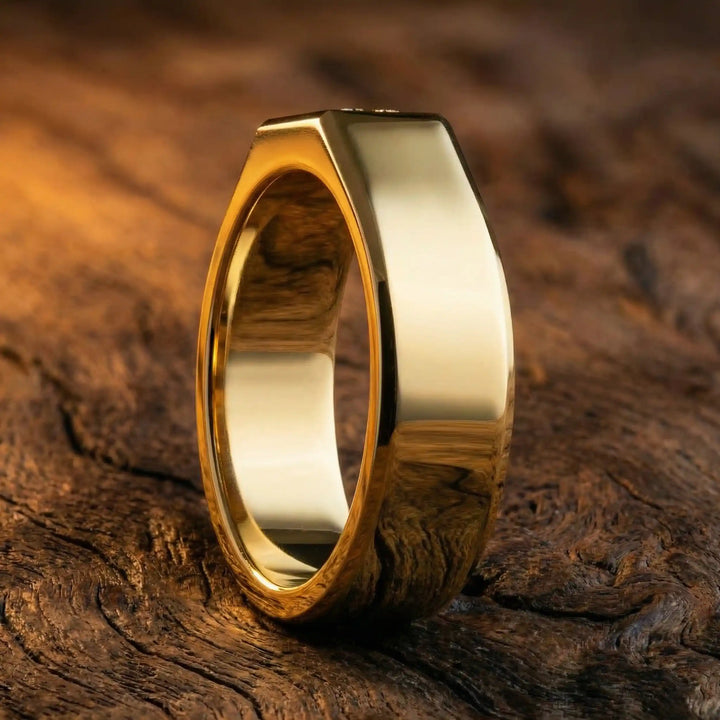 Emerald cut lab-grown diamond bezel ring displayed on wood surface.