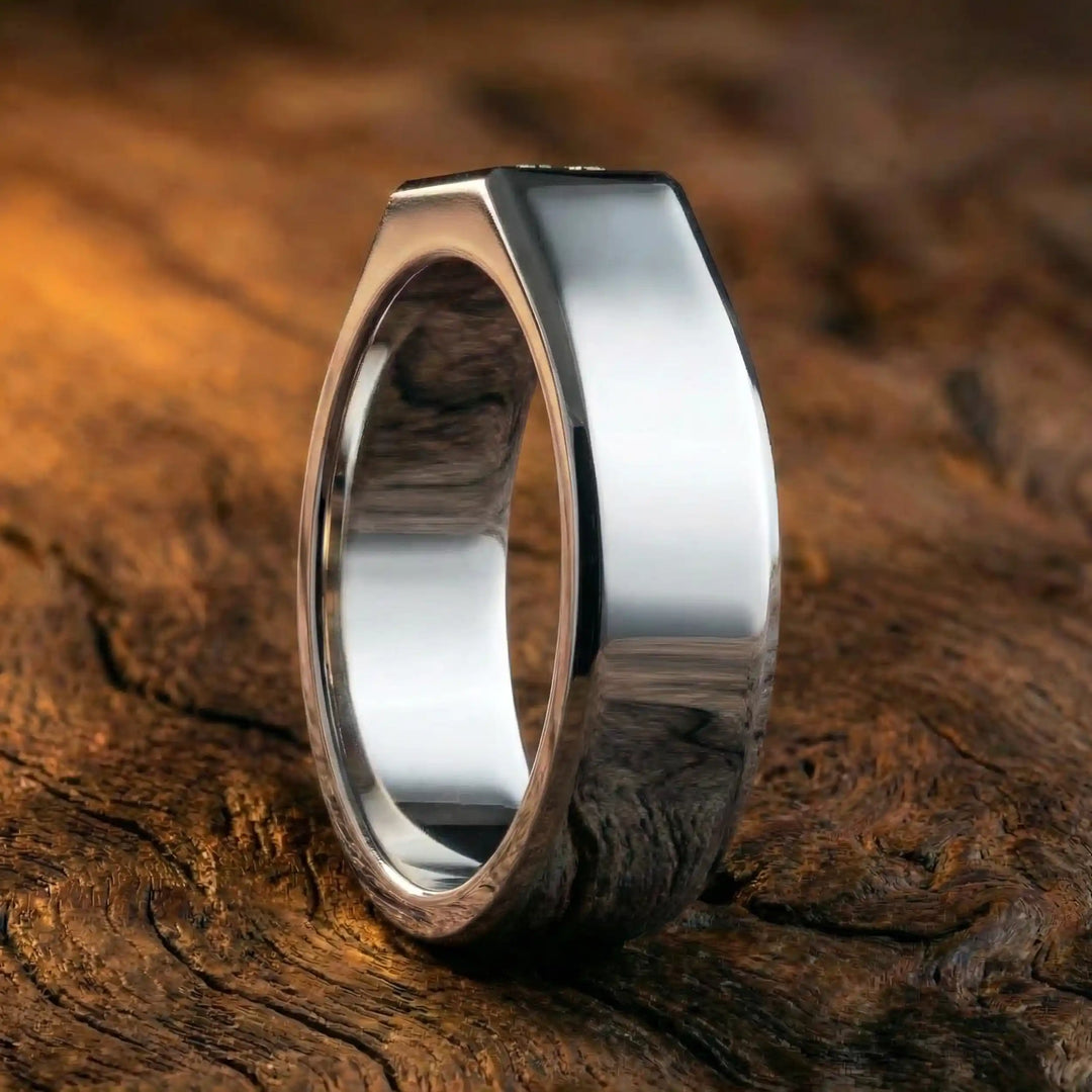 Emerald cut lab-grown diamond bezel ring displayed on wood surface.
