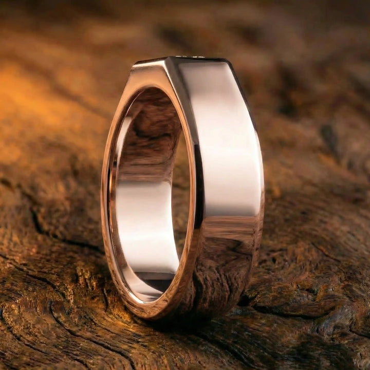 Emerald cut lab-grown diamond bezel ring displayed on wood surface.