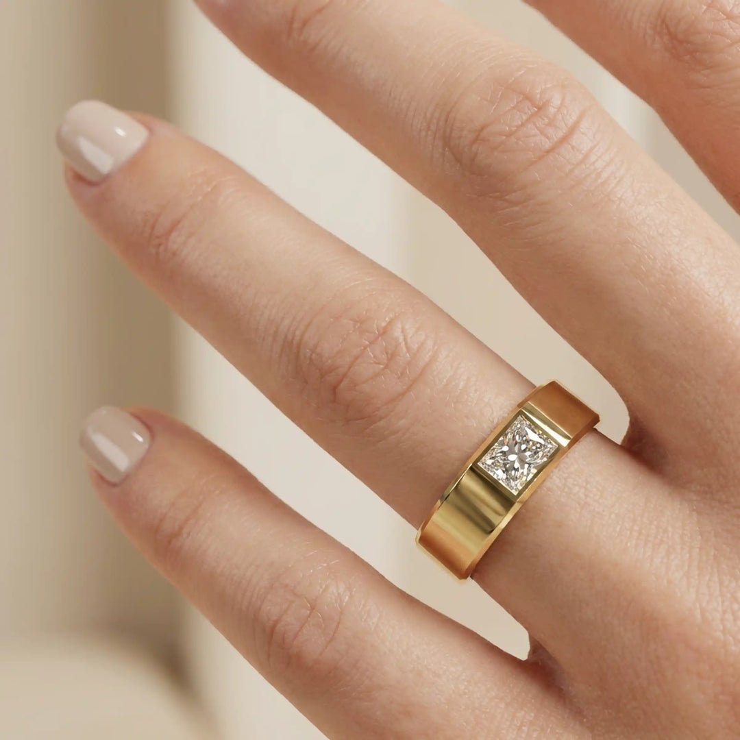 Emerald cut lab-grown diamond bezel ring displayed on hand.