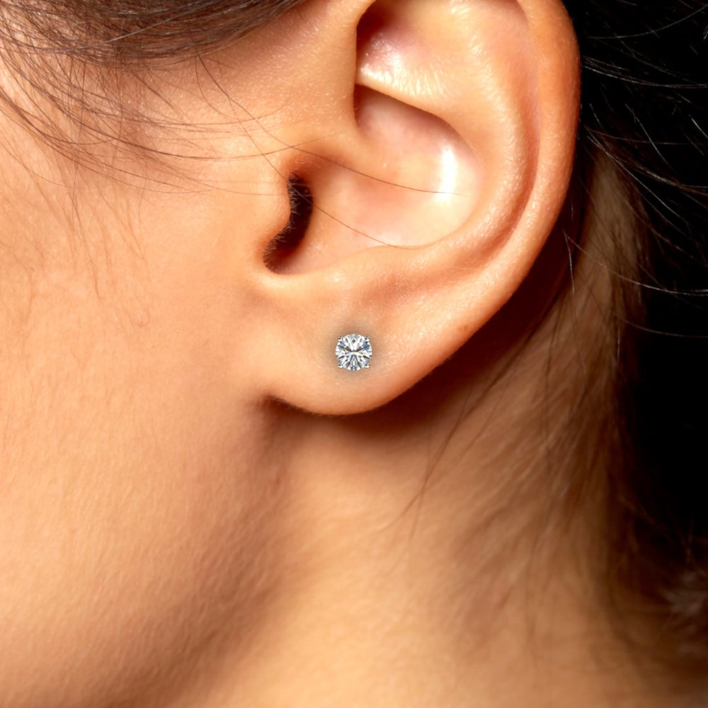 Close-up of 1 carat total round lab-grown diamond stud earring in a four-prong basket setting on an ear.