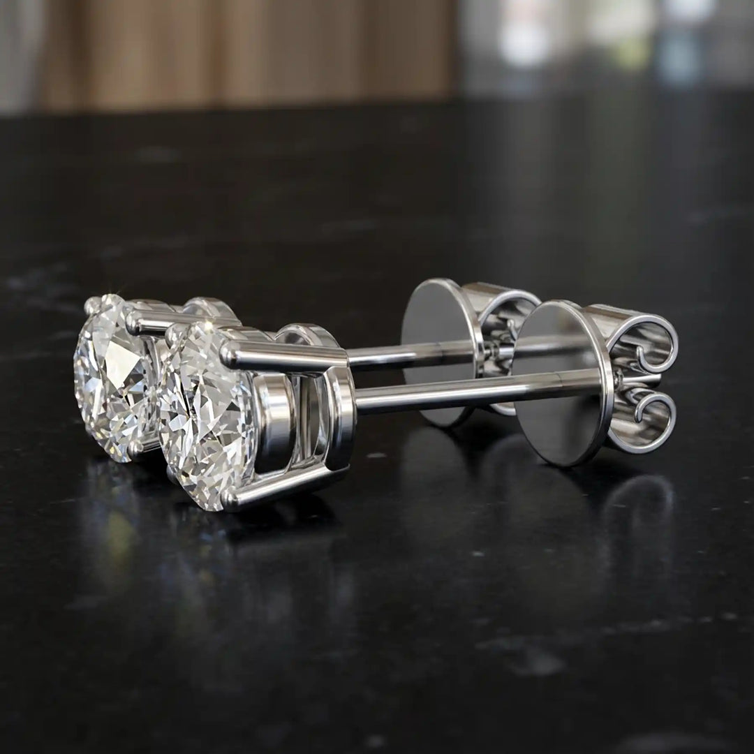 Round lab-grown diamond four-prong basket stud earrings displayed on black surface.