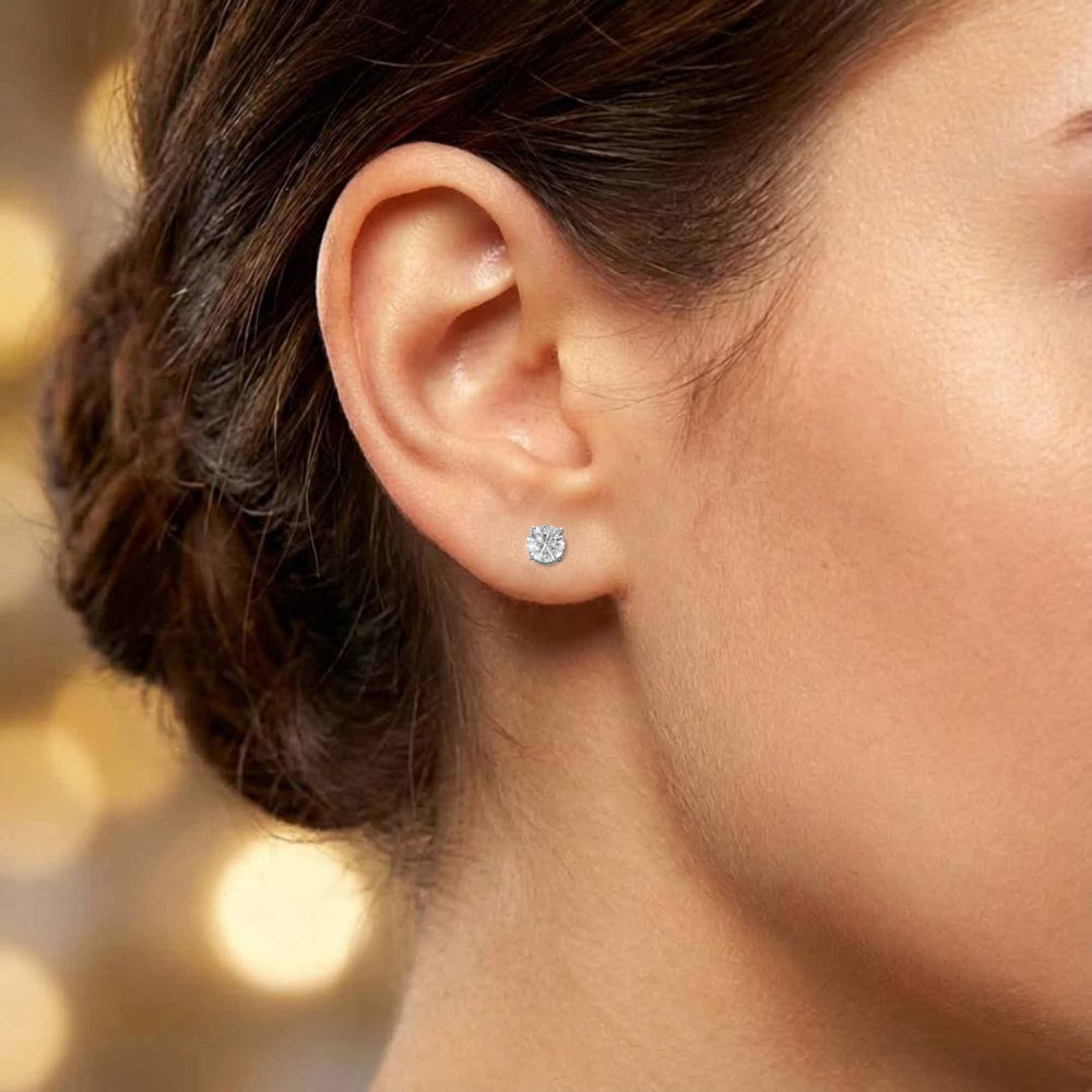 Round lab-grown diamond four-prong basket stud earrings displayed on ear