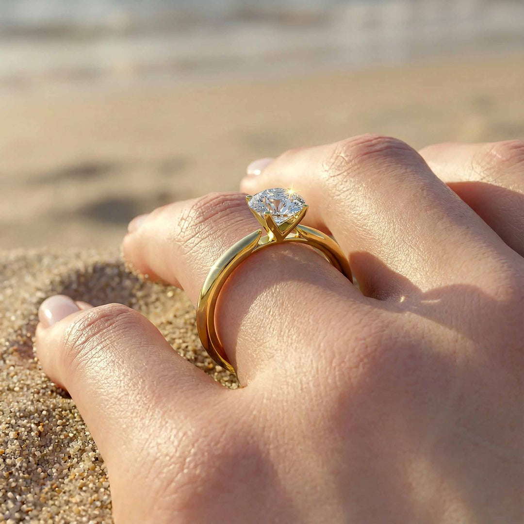 Round diamond cathedral solitaire engagement ring shown on reflective surface.