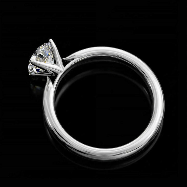Round diamond cathedral solitaire engagement ring shown on reflective surface.