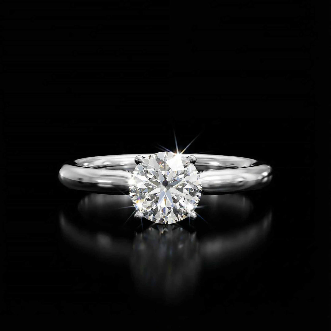 Round diamond cathedral solitaire engagement ring shown on reflective surface.
