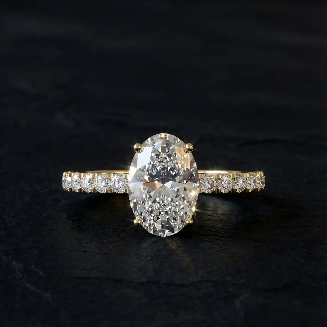 Oval lab diamond pavé engagement ring displayed on dark stone background.