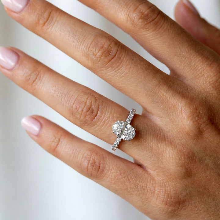Oval lab diamond pavé engagement ring displayed on hand.