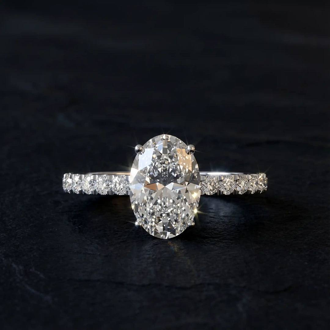 Oval lab diamond pavé engagement ring displayed on dark stone background.