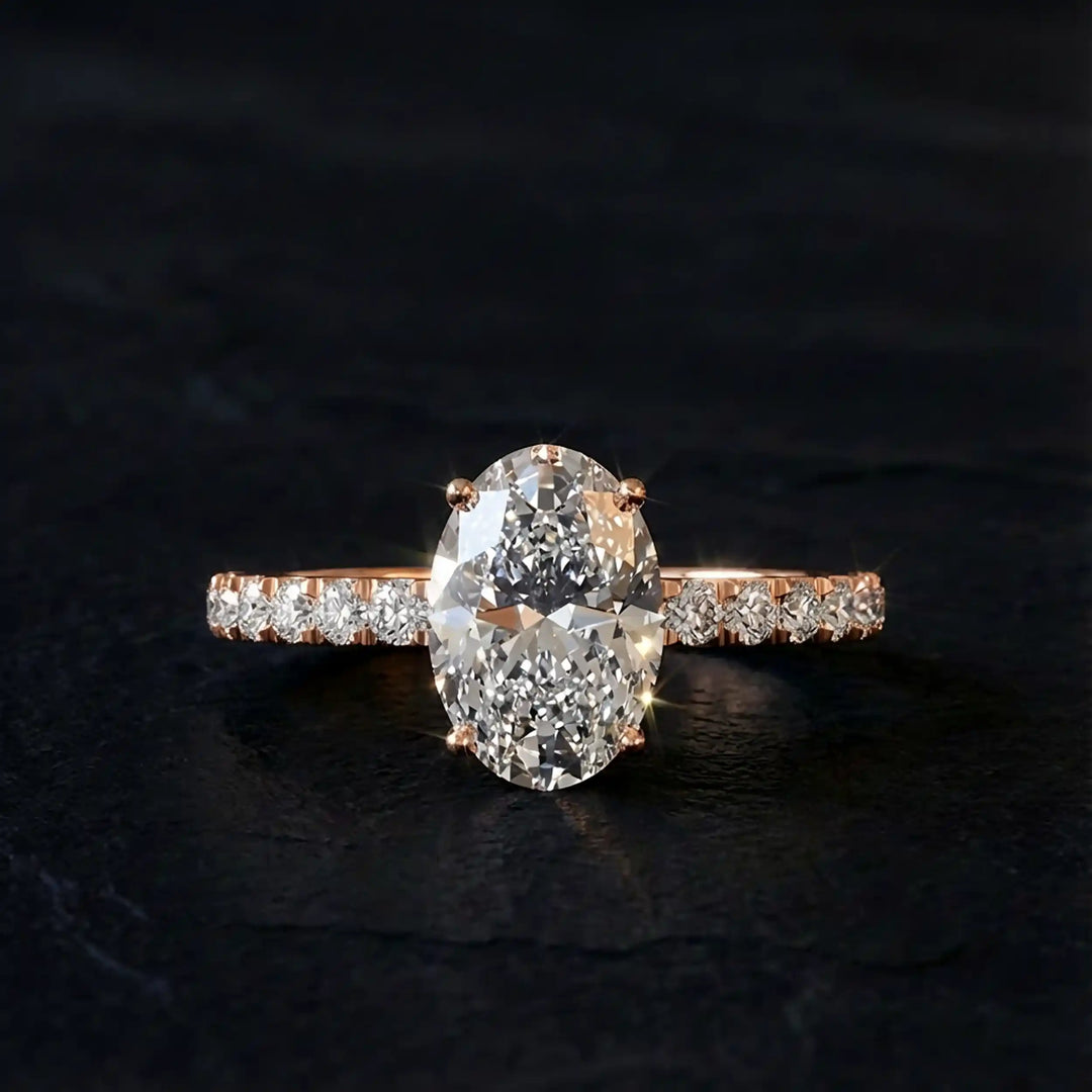 Oval lab diamond pavé engagement ring displayed on dark stone background.