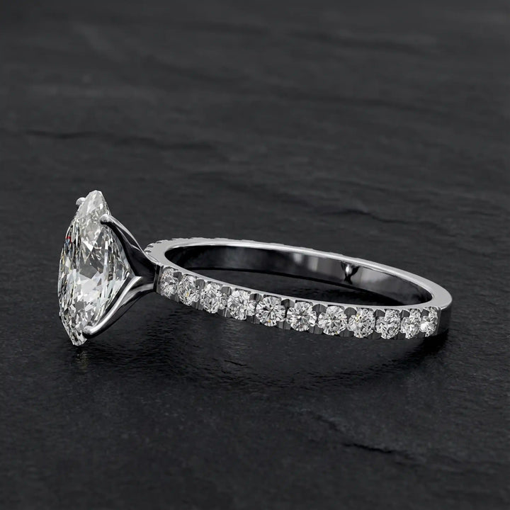 Oval lab diamond pavé engagement ring displayed on dark stone background.