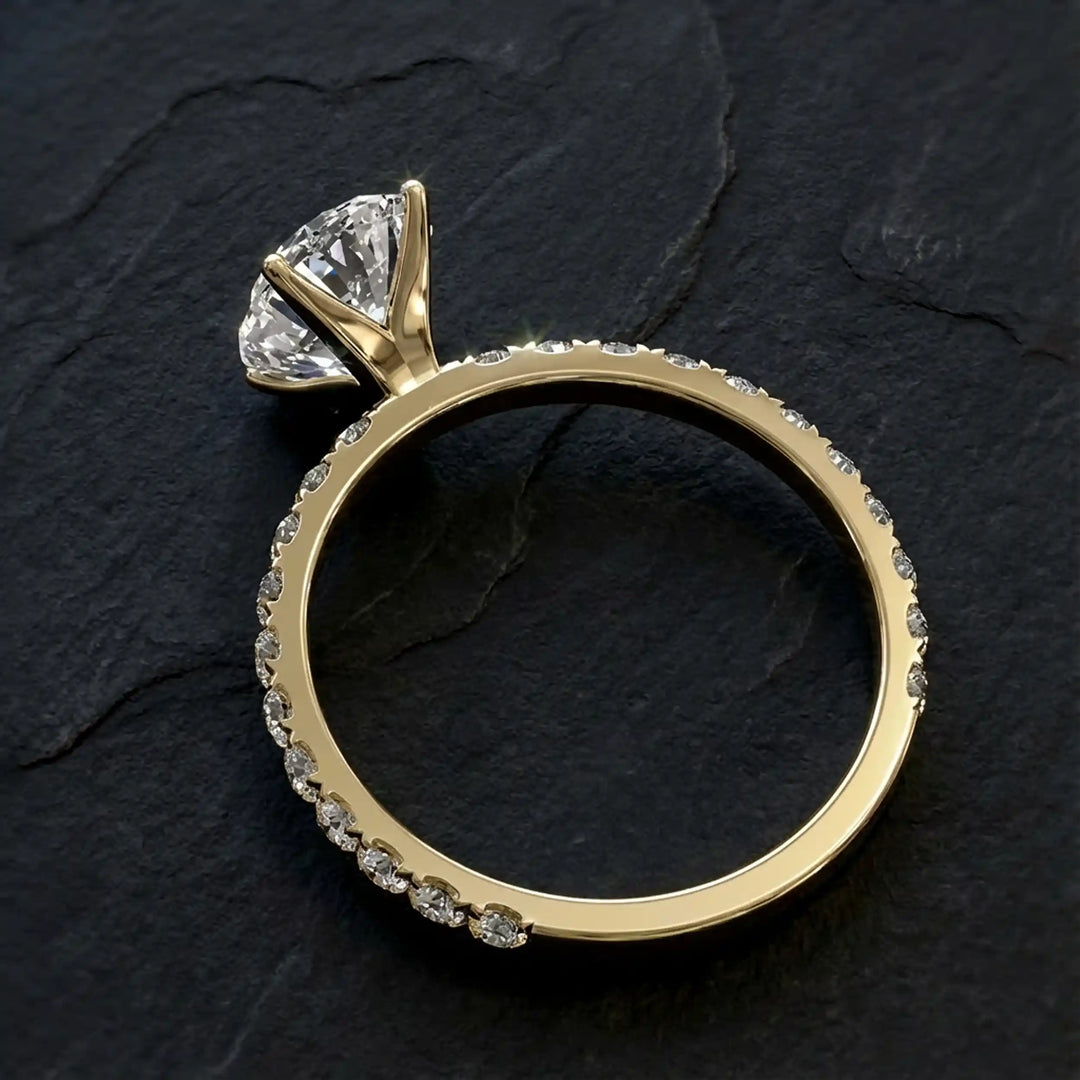 Oval lab diamond pavé engagement ring displayed on dark stone background.