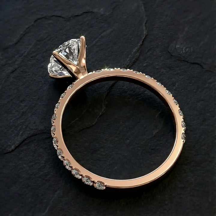 Oval lab diamond pavé engagement ring displayed on dark stone background.