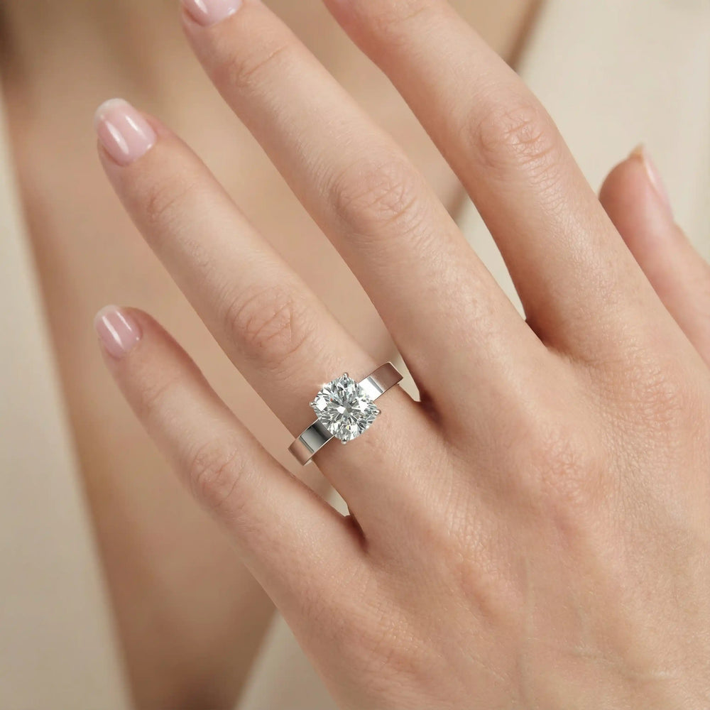 Elongated cushion lab grown diamond solitaire ring on wide flat band shown on hand.