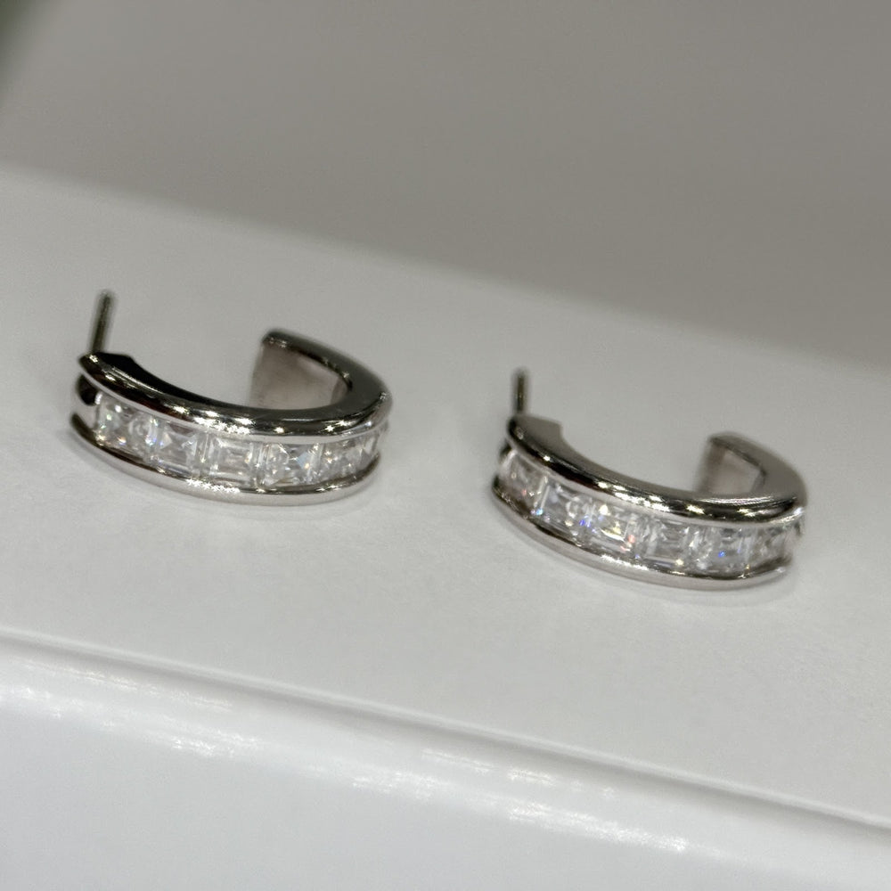 14k white gold moissanite three-quarter hoops lying flat, posts visible