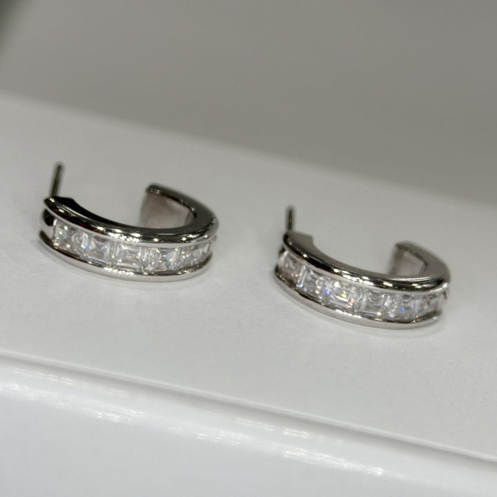 14k white gold moissanite three-quarter hoops lying flat, posts visible