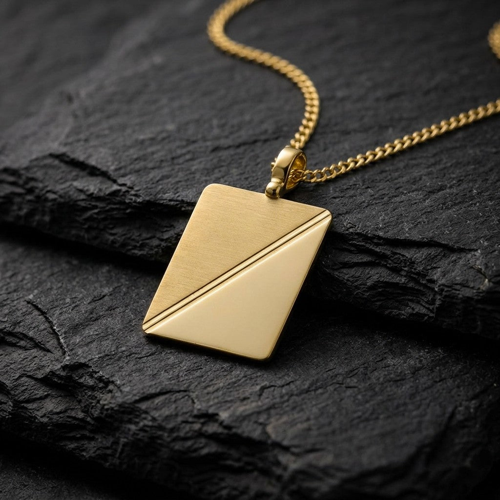 10K yellow gold rectangular tag pendant with diagonal satin and polished halves, 26.8 x 21 mm, 0.4 mm thick, on a yellow gold chain resting on dark slate stone