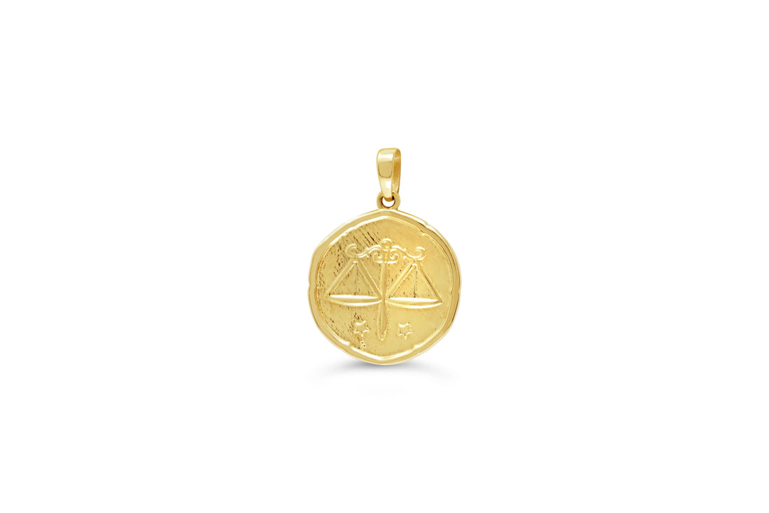 10K yellow gold Libra zodiac pendant: a round medallion with the balance scales raised in polished gold and small stars on a textured background