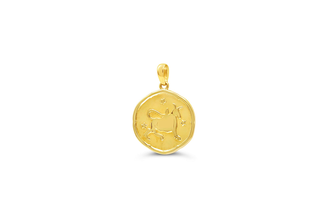 10K yellow gold Taurus zodiac pendant: a round medallion with a charging bull raised in polished gold and small stars on a textured background