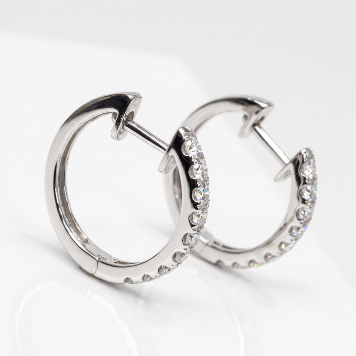 Staggered studio angle of RUDIX 18k white gold natural diamond huggie hoop earrings showing hinged huggie closures