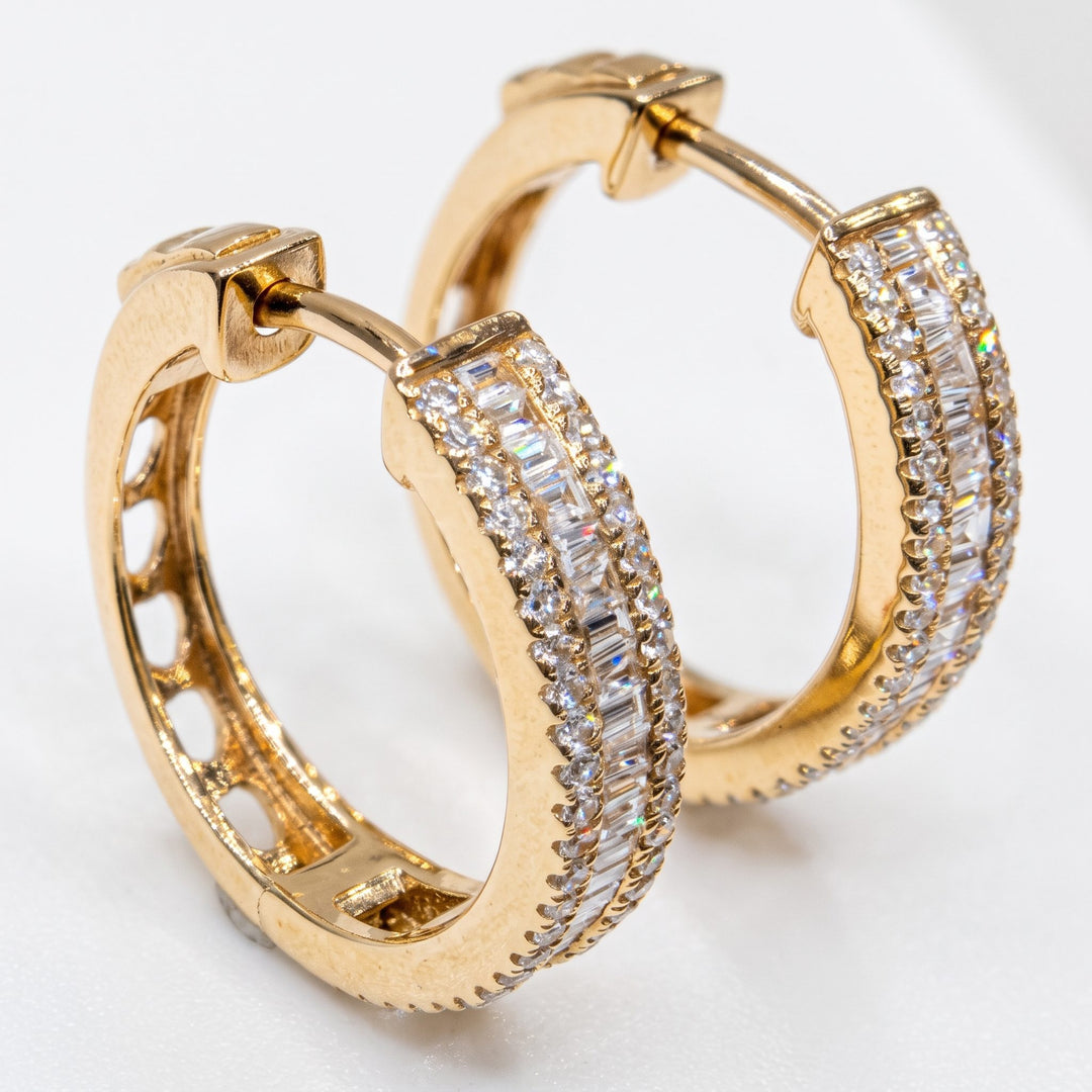 Angled studio shot of RUDIX 14k yellow gold natural diamond baguette huggie hoop earrings showing hinged closures