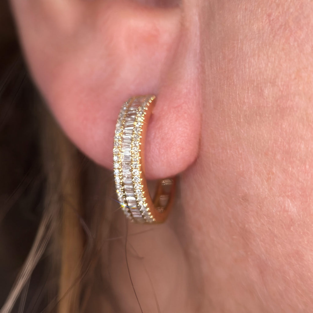 On-ear close-up of a 14k yellow gold natural diamond baguette huggie hoop earring by RUDIX on the earlobe