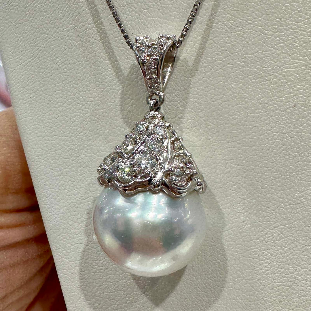 Hand holding a 16.6mm white South Sea pearl pendant in 18K white gold, adorned with small diamonds.