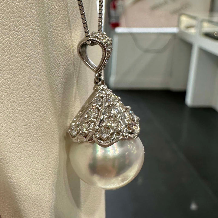 Hand holding a 16.6mm white South Sea pearl pendant in 18K white gold, adorned with small diamonds.