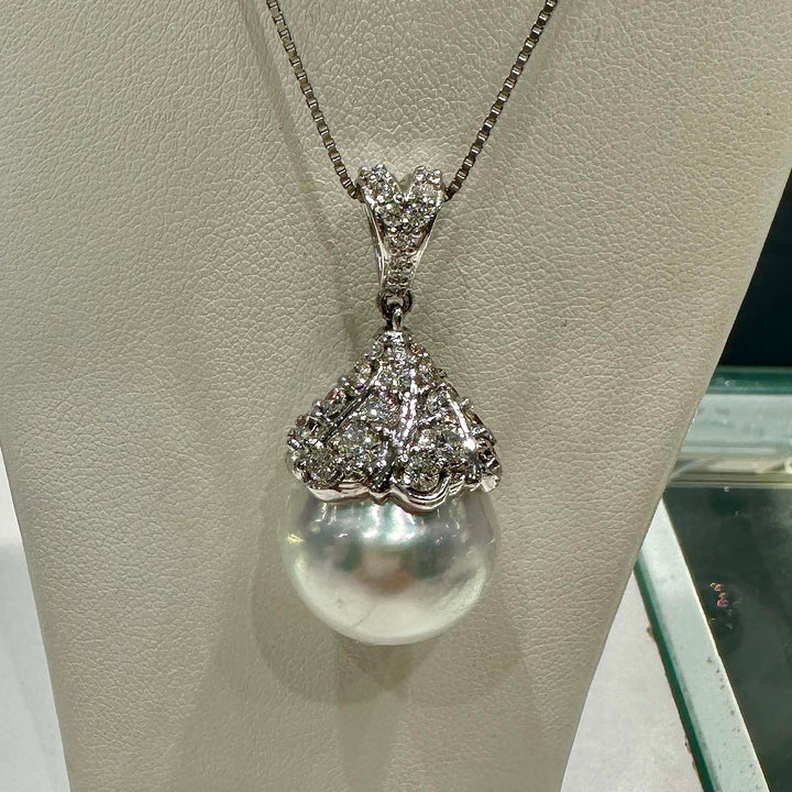 Hand holding a 16.6mm white South Sea pearl pendant in 18K white gold, adorned with small diamonds.