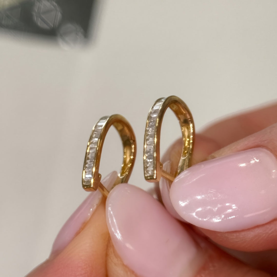 14k yellow gold natural diamond baguette huggies held in hand, posts visible