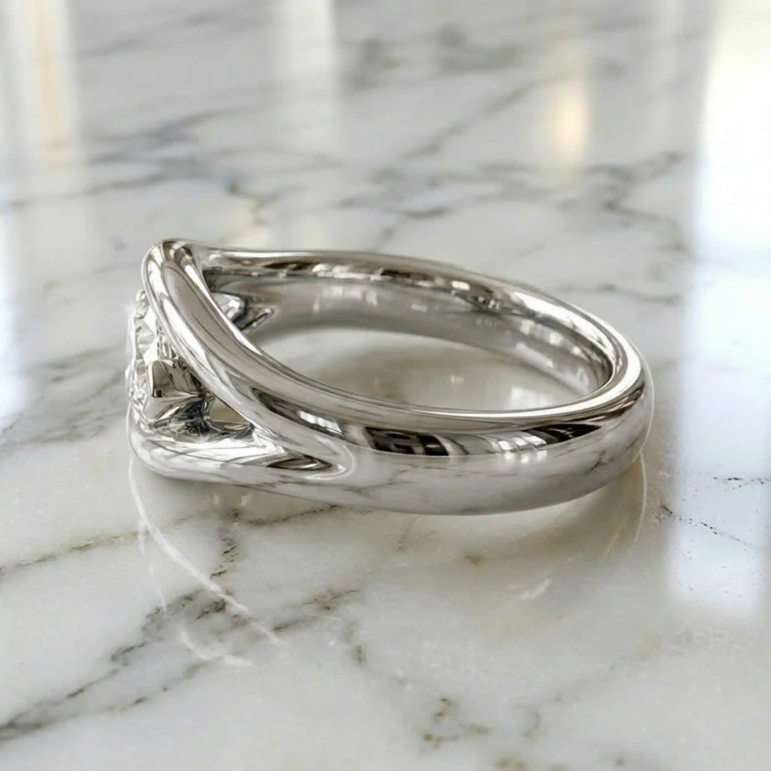 Marquise lab-grown diamond solitaire split shank engagement ring displayed on stone surface.
