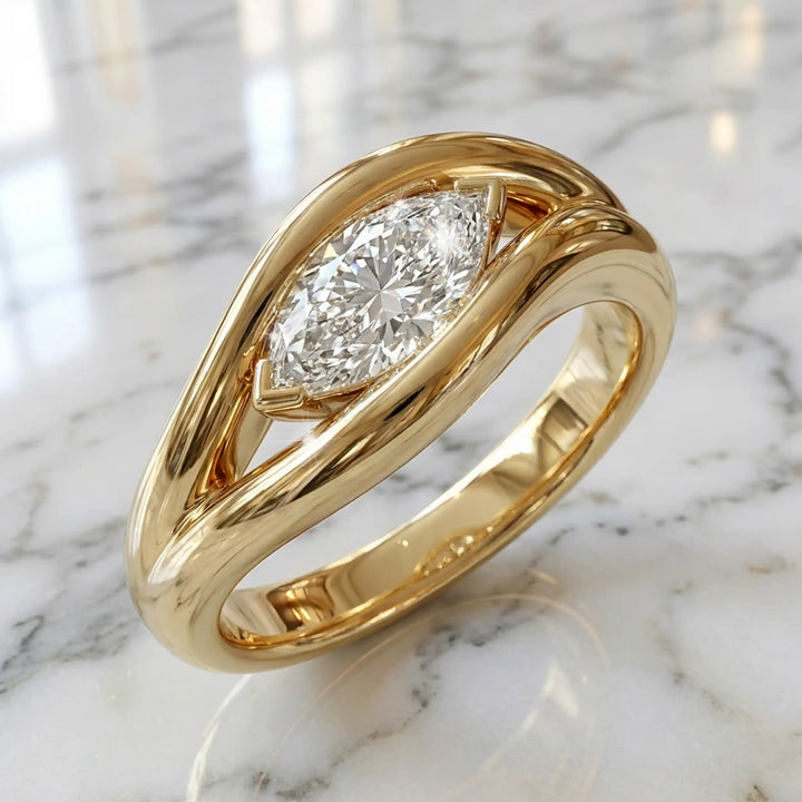 Marquise lab-grown diamond solitaire split shank engagement ring displayed on stone surface.
