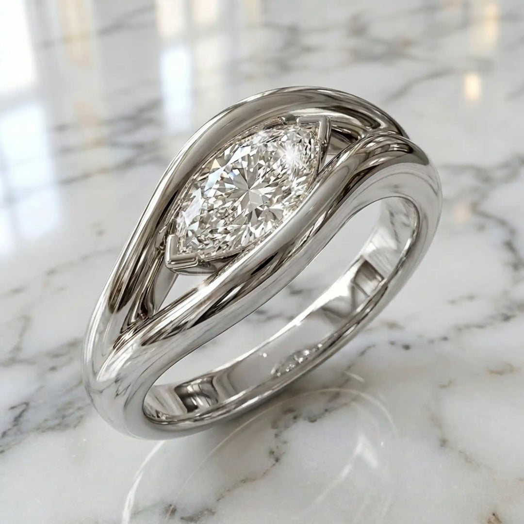 Marquise lab-grown diamond solitaire split shank engagement ring displayed on stone surface.
