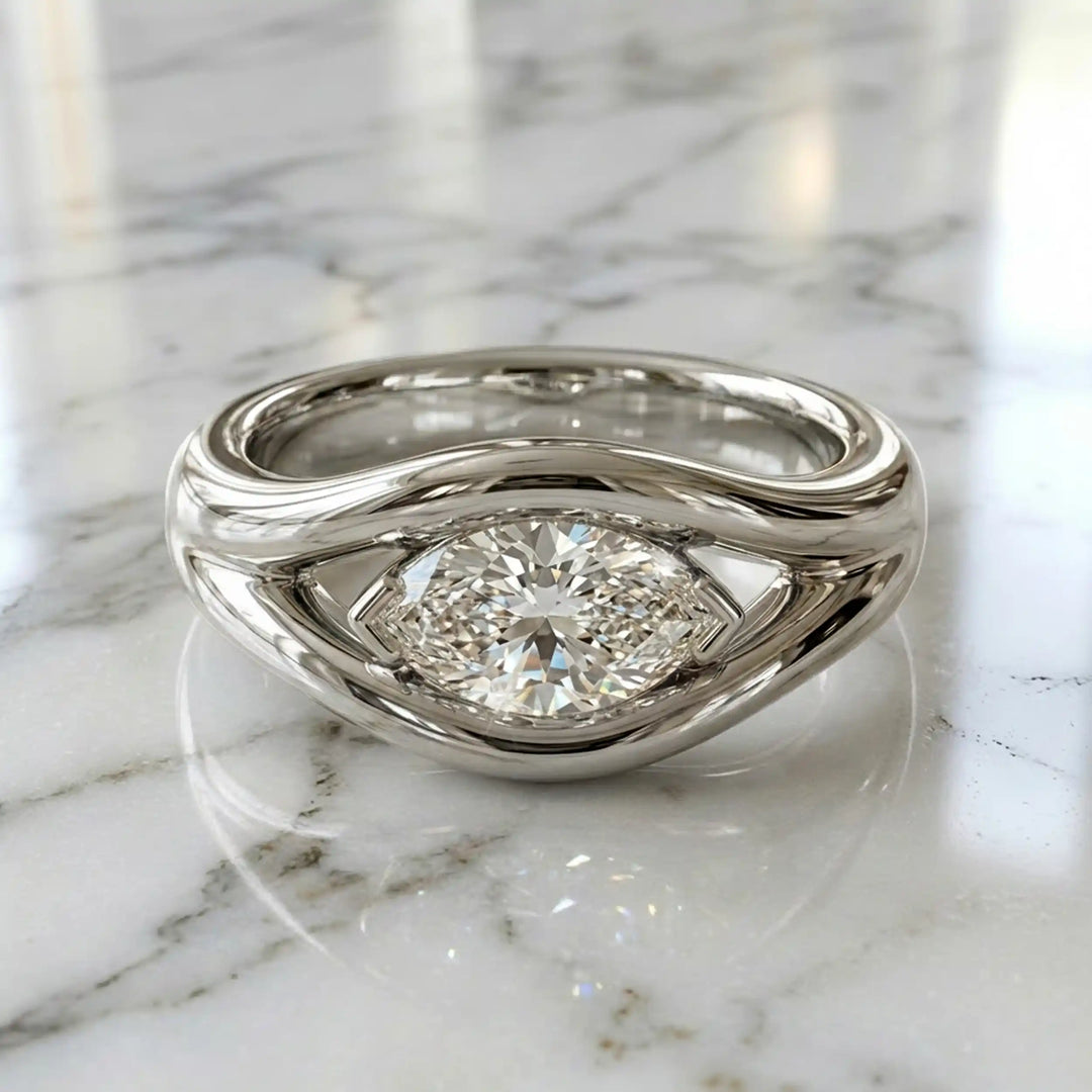 Marquise lab-grown diamond solitaire split shank engagement ring displayed on stone surface.
