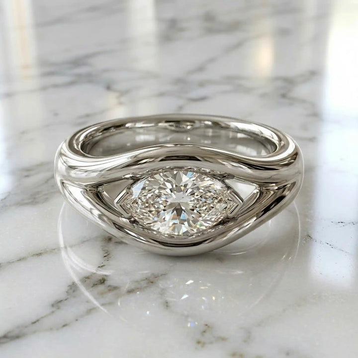 Marquise lab-grown diamond solitaire split shank engagement ring displayed on stone surface.
