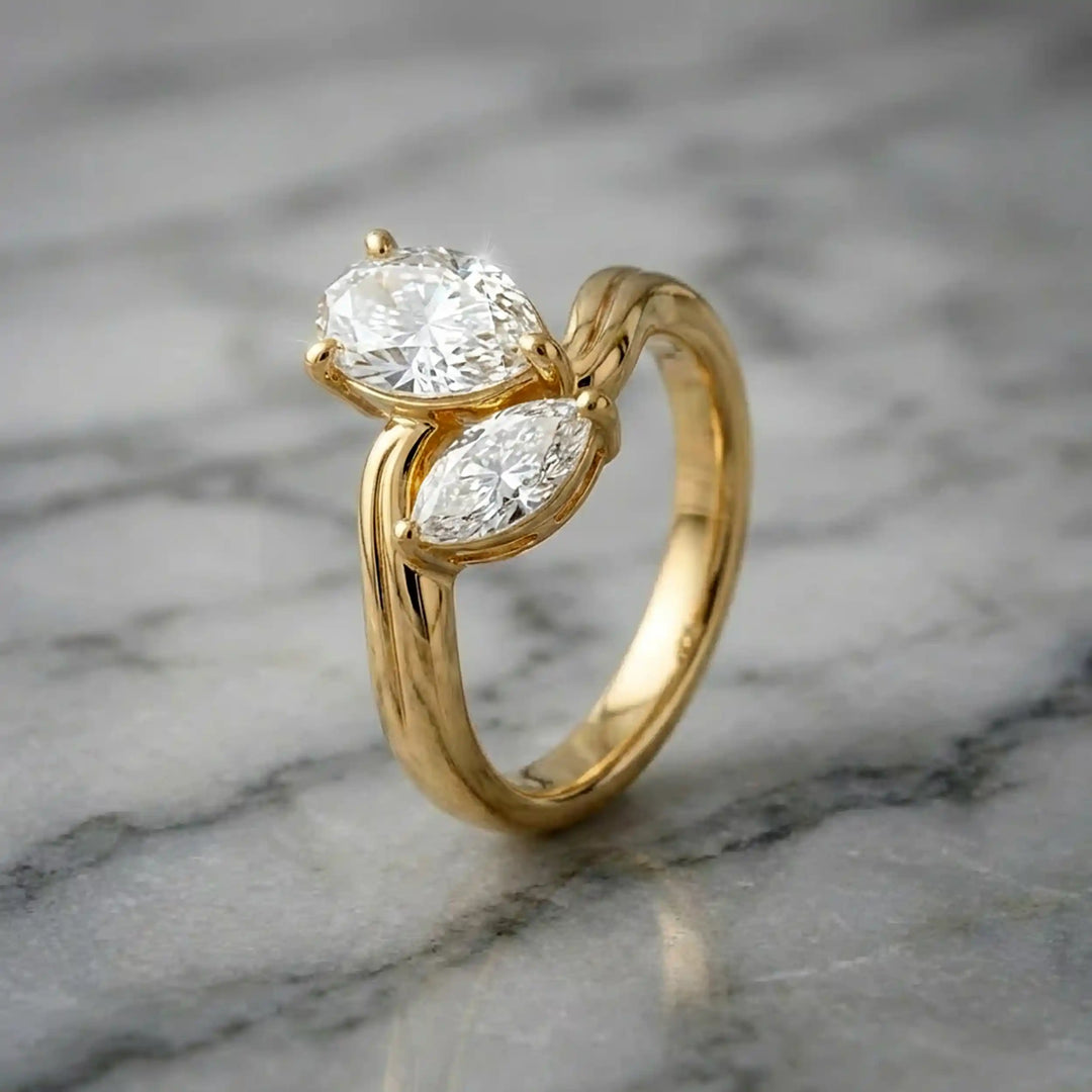 Lab-grown pear and marquise diamond toi et moi solitaire engagement ring displayed on marble surface.

