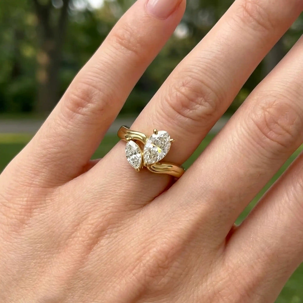 Lab-grown pear and marquise diamond toi et moi solitaire engagement ring displayed on hand.
