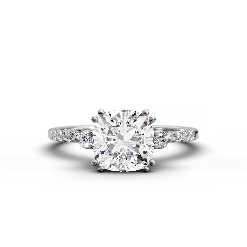 Cushion diamond three-stone engagement ring with pavé band shown in studio lighting.