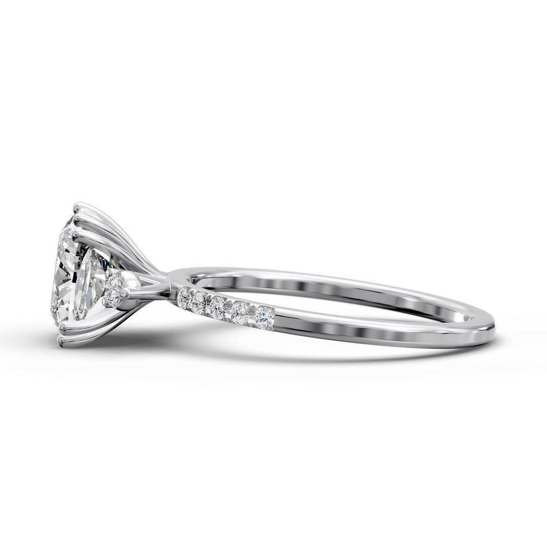 Cushion diamond three-stone engagement ring with pavé band shown in studio lighting.