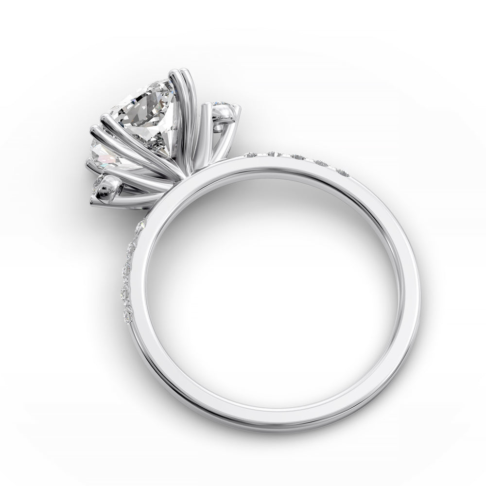 Cushion diamond three-stone engagement ring with pavé band shown in studio lighting.