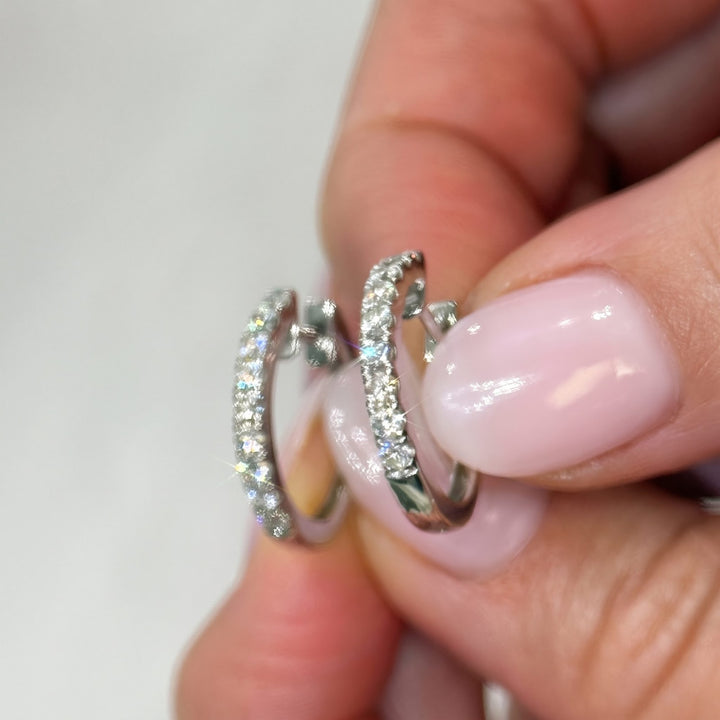 Hand holding RUDIX 18k white gold natural diamond huggie hoop earrings showing diamond fire and petite scale