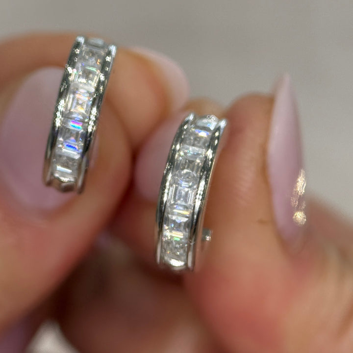14k white gold moissanite three-quarter hoops held in hand